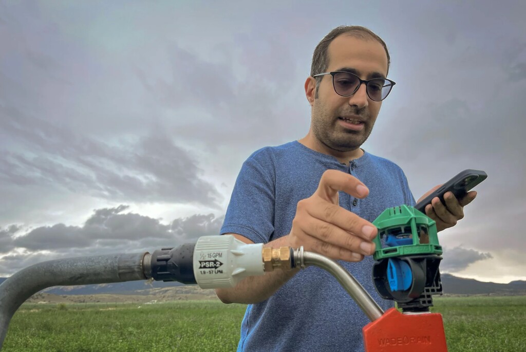 (David Condos | KUER) Utah State University researcher Maziyar Vaez Roudbari demonstrates a water-efficient rotator nozzle he’s testing at a farm in Wayne County, Aug. 22, 2024. Showing Utah farmers which equipment can squeeze the best possible harvests from their water could help sustain them in a drier future.