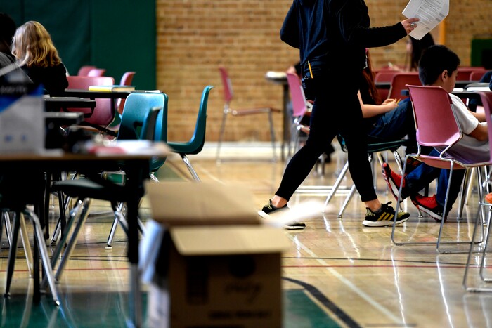 A teacher moves from table-to-table while teaching one of two combined sixth-grade classes in the gymnasium at Skinner Middle School during the first day of the Denver Public Schools teachers strike, Monday, Feb. 11, 2019, in Denver. More negotiations are set for Tuesday. (Joe Amon/The Denver Post via AP)