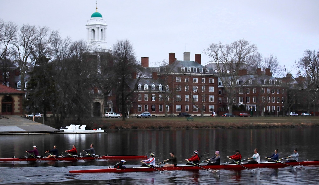 FILE-- In this March 7, 2017 file photograph, rowers pass the campus of Harvard University as they paddle down the Charles River in Cambridge, Mass.  Harvard and the group Students for Fair Admissions will file dueling analyses of the Ivy League school's admissions data in a lawsuit alleging discrimination against Asian-American applicants. (AP Photo/Charles Krupa)
