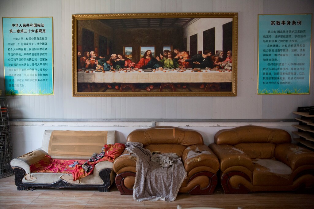 (AP Photo/Ng Han Guan) In this photo taken Monday, June 4, 2018, a painting of the Last Supper is seen next to posters quoting China's constitution on religious freedom in a house church shut down by authorities near the city of Nanyang in central China's Henan province. Under President Xi Jinping, China's most powerful leader since Mao Zedong, believers are seeing their freedoms shrink dramatically even as the country undergoes a religious revival. Experts and activists say that as he consolidates his power, Xi is waging the most severe systematic suppression of Christianity in the country since religious freedom was written into the Chinese constitution in 1982.