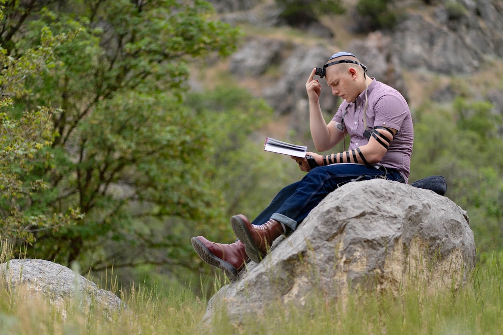 (Francisco Kjolseth | The Salt Lake Tribune) Jacob Feldon, a queer Jewish student who is about to be a senior at Logan High School, does his weekday morning prayer in Dry Canyon on Thursday, June 30, 2022. Tefillin, a set of small black leather boxes with leather straps containing scrolls of parchment inscribed with verses from the Torah, is used by Feldon during his weekday morning prayer, which allows him to connect to God.