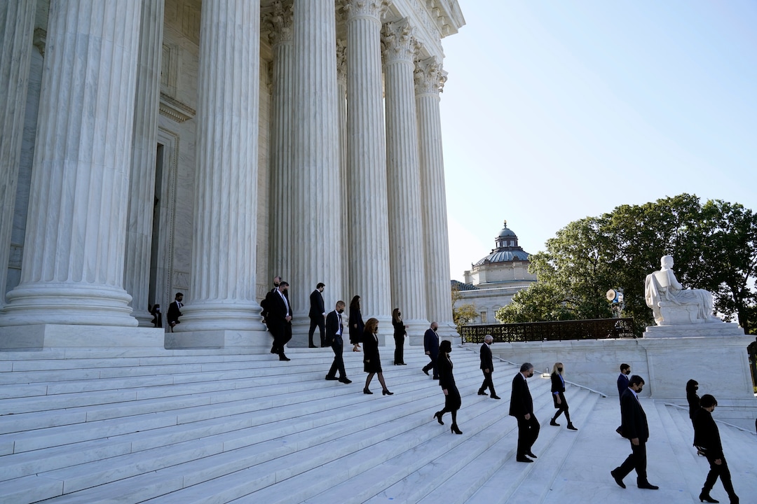 Former law clerks for Justice Ruth Bader Ginsburg stand socially distanced on the steps of the Supreme Court as they await the arrival of the casket of Ginsburg to arrive at the Supreme Court in Washington, Wednesday, Sept. 23, 2020. Ginsburg, 87, died of cancer on Sept. 18. (AP Photo/Alex Brandon, Pool)