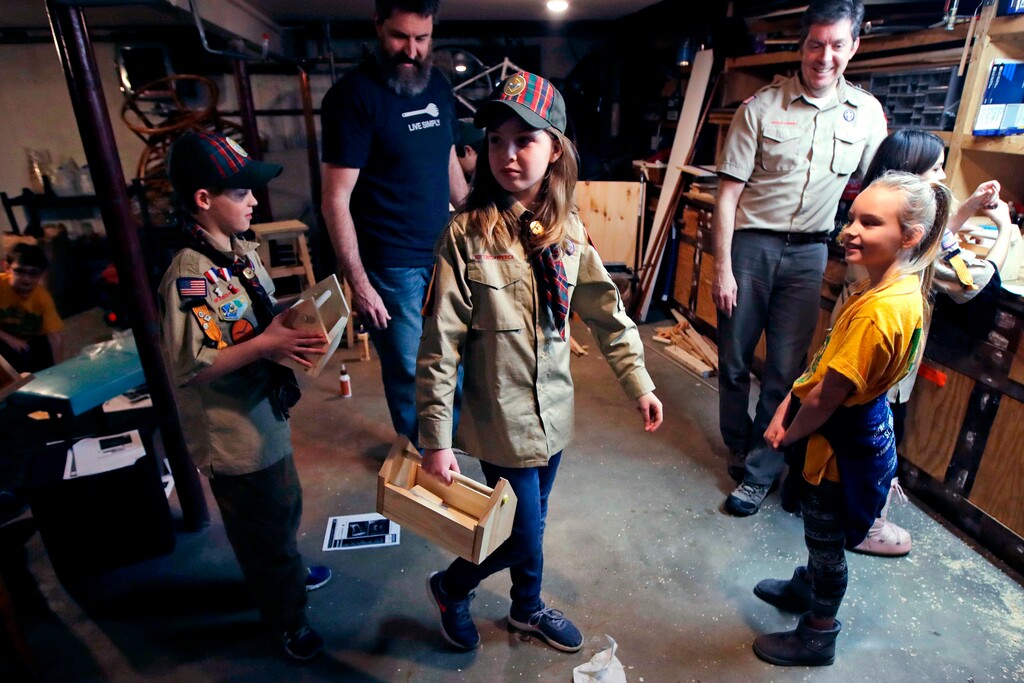 (Charles Krupa | The Associated Press) In this March 1, 2018, file photo, Tatum Weir, center, carries a tool box she built as her twin brother Ian, left, follows after a Cub Scout meeting in Madbury, N.H. Fifteen communities in New Hampshire are part of an "early adopter" program to allow girls to become Cub Scouts and eventually Boy Scouts. For 108 years, the Boy Scouts of America's flagship program for older boys has been known simply as the Boy Scouts. With girls soon entering the ranks, the BSA says that iconic name will change to “Scouts BSA.” The change will take effect in February 2019.