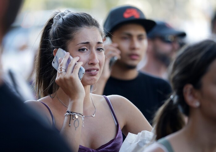 People speak on their phones as they stand on a street in Barcelona, Spain, Thursday, Aug. 17, 2017. Police in the northern Spanish city of Barcelona say a white van has jumped the sidewalk in the city's historic Las Ramblas district, injuring several people. (AP Photo/Manu Fernandez)