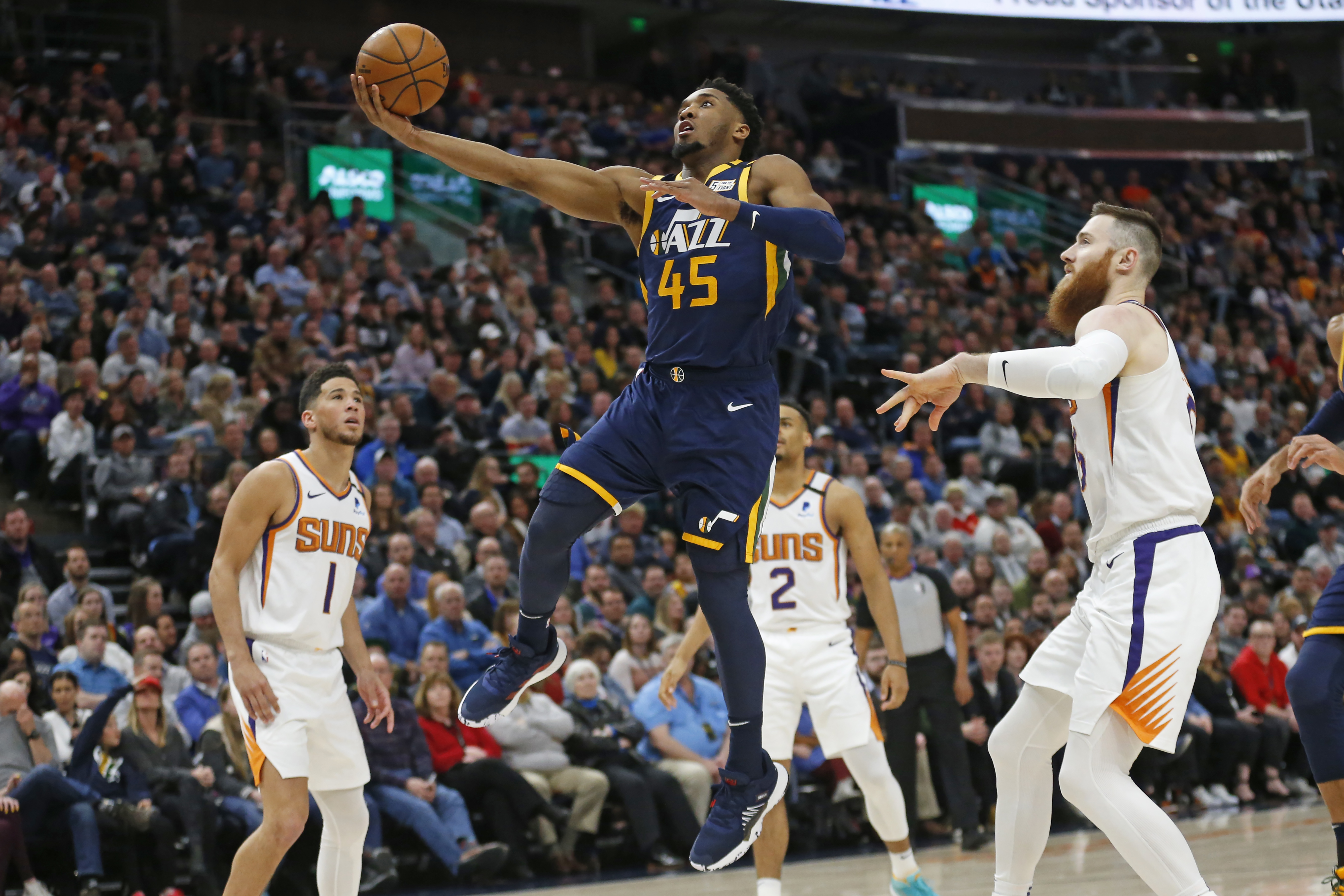 Utah Jazz guard Donovan Mitchell (45) goes to the basket as Phoenix Suns' Devin Booker (1) and Aron Baynes, right, watch in the first half during an NBA basketball game Monday, Feb. 24, 2020, in Salt Lake City. (AP Photo/Rick Bowmer)