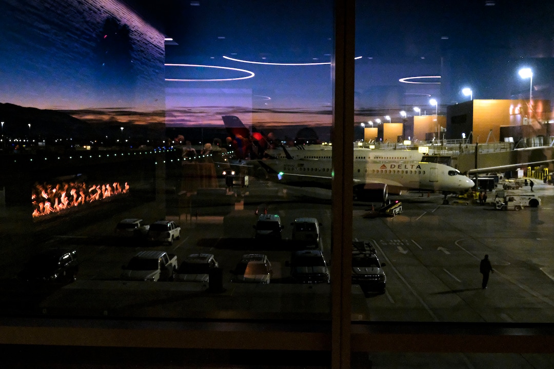 (Leah Hogsten  |  The Salt Lake Tribune) The Salt Lake City International Airport commemorated its 100-year anniversary, Dec. 21, 2020. Reflections of party attendees are reflected in the glass within the Greeting Room as a Delta Jet prepares to leave the hub.