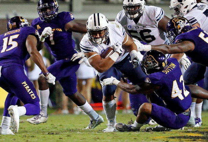 BYU's Ula Tolutau (5) tries to break away from East Carolina's Devon Sutton (42) and others tacklers during the first half of an NCAA college football game in Greenville, N.C., Saturday, Oct. 21, 2017. (AP Photo/Karl B DeBlaker)