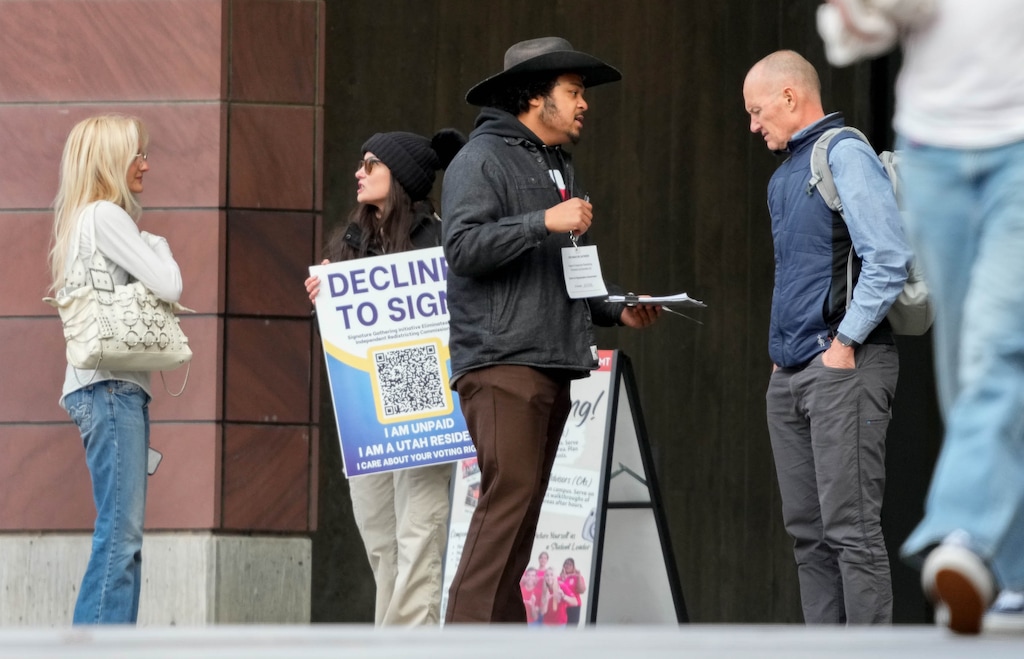 (Francisco Kjolseth | The Salt Lake Tribune) A paid signature gatherer, center, reaches out to Utah voters at the University of Utah Marriott Library in the ongoing effort to repeal Prop 4, the 2018 voter-approved ballot initiative on redistricting, on Thursday, Jan. 8, 2026. University alumni and unpaid volunteer Lauren Miller, center left, was on hand to oppose the effort being put forth by the Utah Republican Party.