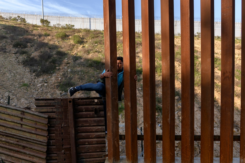 An Honduran migrant climbs the U.S. border fence to jump inside the United States to San Diego, from Tijuana, Mexico, Monday, Dec. 24, 2018. In the Southwest, growing diversity and the president’s demeaning rhetoric about Latino migrants are pulling parts of the region from the once-firm grip of Republicans. (AP Photo/Daniel Ochoa de Olza)