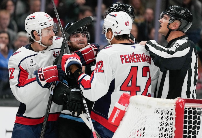 (Francisco Kjolseth | The Salt Lake Tribune) Utah Hockey Club center Alexander Kerfoot (15) is grabbed by Washington Capitols players after knocking off the helmet of their goalie during an NHL hockey game at the Delta Center in Salt Lake City on Monday, Nov. 18, 2024.