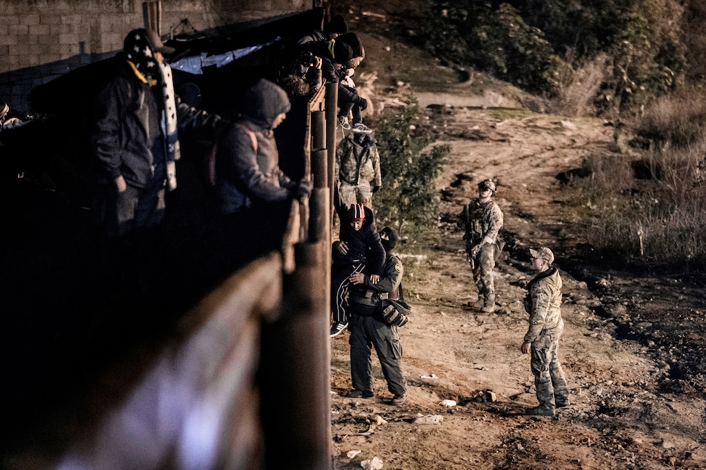 A U.S. Border Protection officer grabs a migrant as he goes down the border fence to get into the U.S. side in San Diego, Calif., from Tijuana, Mexico, Tuesday, Jan. 1, 2019. Discouraged by the long wait to apply for asylum through official ports of entry, many migrants from recent caravans are choosing to cross the U.S. border wall and hand themselves in to border patrol agents. (AP Photo/Daniel Ochoa de Olza)