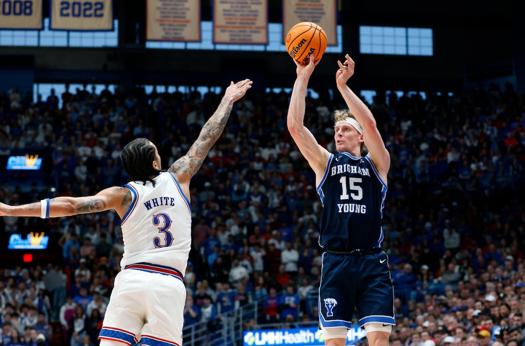 BYU guard Richie Saunders (15) prepares to shoot a 3-point basket as Kansas guard Tre White (3) defends during the second half of an NCAA college basketball game, Saturday, Jan. 31, 2026, in Lawrence, Kan. (AP Photo/Colin E. Braley)