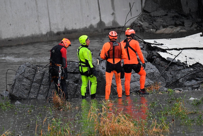Rescuers work among the rubble of the collapsed Morandi highway bridge in Genoa, northern Italy, Tuesday, Aug. 14, 2018. A large section of the bridge collapsed over an industrial area in the Italian city of Genova during a sudden and violent storm, leaving vehicles crushed in rubble below. (Luca Zennaro/ANSA via AP)
