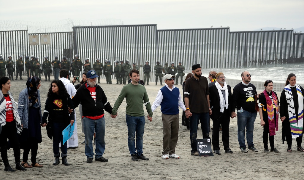 (Gregory Bull | The Associated Press) People hold hands in prayer during a protest near the border with Tijuana, Mexico, Monday, Dec. 10, 2018, in San Diego. U.S. Border Patrol agents have handcuffed more than a dozen people participating in a demonstration organized by a Quaker group at the U.S.-Mexico border, calling for the end of the detention and deportation of immigrants and the militarization of the border.