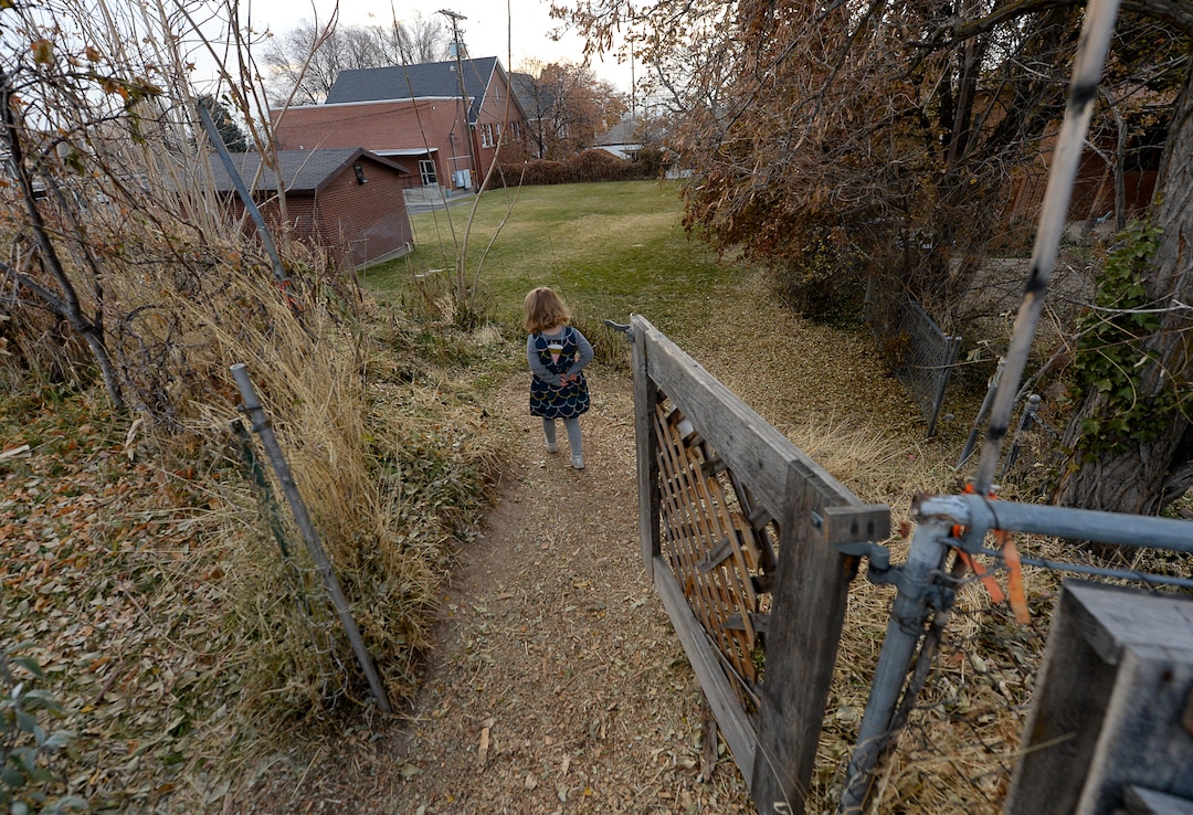 (Francisco Kjolseth  |  The Salt Lake Tribune)  Oona Barrett, 4, walks out of the community garden where her family grows on one of 42 plots at the garden. The garden has operated on church land for 43 years behind the 33rd Ward House, in background.
