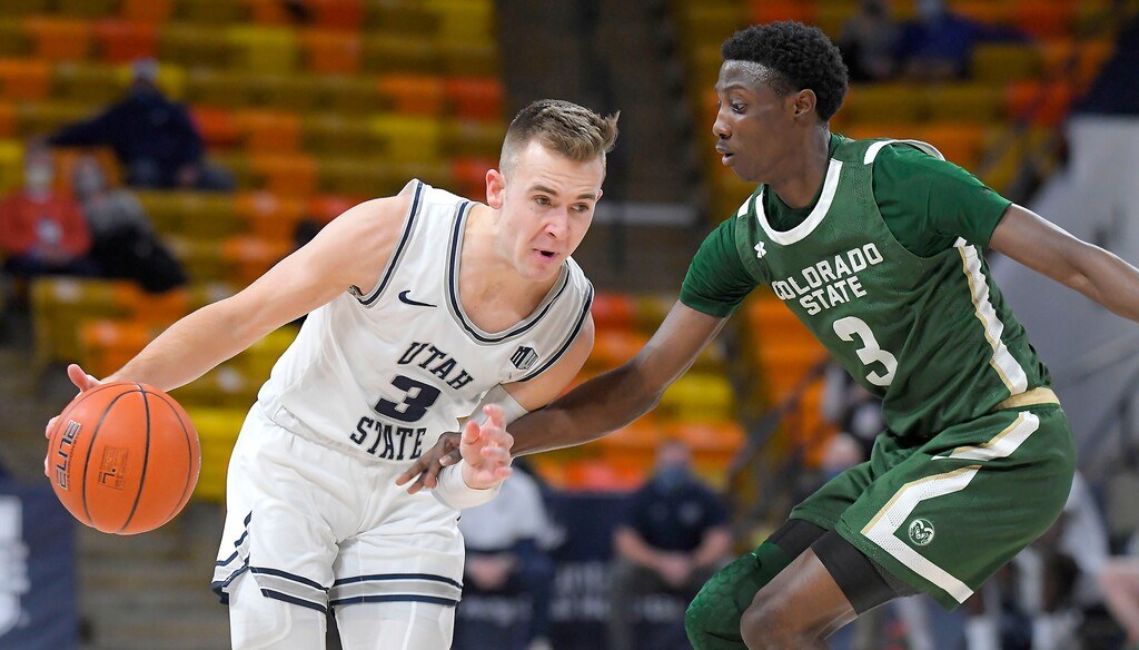 (Eli Lucero/The Herald Journal via AP, pool photo) Utah State guard Steven Ashworth, left, dribbles the ball as Colorado State guard Kendle Moore defends during the first half of an NCAA college basketball game Tuesday, Jan. 19, 2021, in Logan, Utah.