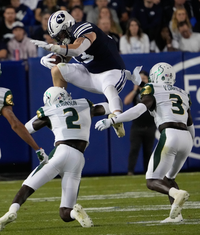 (Francisco Kjolseth | The Salt Lake Tribune) Brigham Young Cougars fullback Masen Wake (13) tries to hurdle South Florida Bulls defensive back TJ Robinson (2) n game action between the Brigham Young Cougars and the South Florida Bulls at LaVell Edwards Stadium in Provo, Saturday, Sept. 25, 2021.