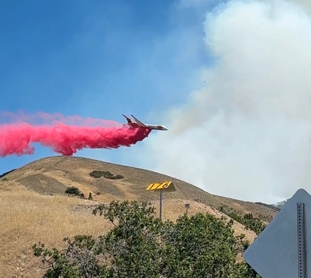 (Jeff Parrott) A large air tanker from Hill Air Force Base drops red fire retardant on the Bonnville Fire in Salt Lake City on Sunday, June 21, 2026. The fire started on Saturday in the foothills behind the University of Utah.