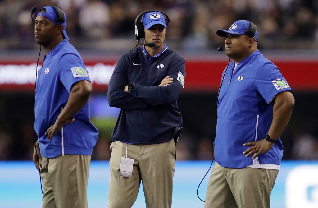 BYU head coach Kalani Sitake (right) discusses strategy with assistant head coach Ed Lamb (middle) and cornerbacks coach Jernaro Gilford (left) during a recent game. Sitake could lose a coach or two to Utah State, which has hired Gary Andersen to replace Matt Wells.