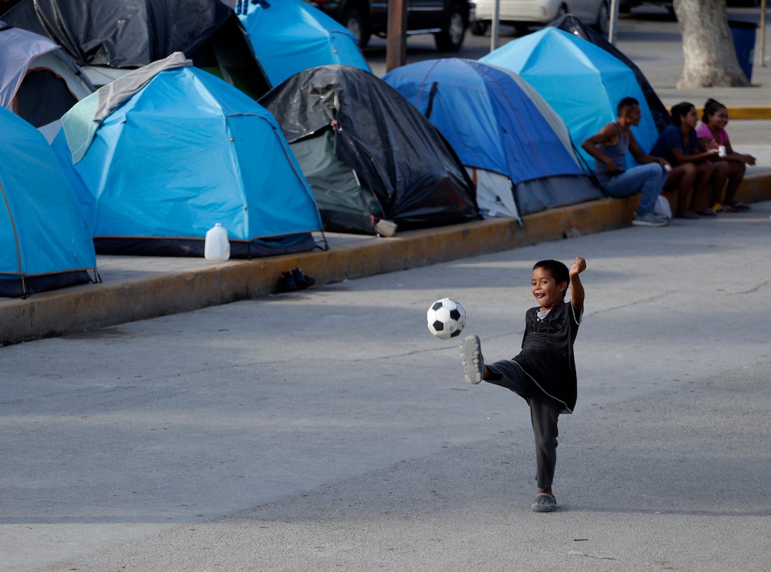 In this Tuesday, Nov. 5, 2019, photo, a young boy plays soccer in a refugee camp in Matamoros, Mexico. The camp is an outgrowth of the Trump administration’s “Remain in Mexico” program, in which more than 55,000 migrants seeking entry into the U.S. have been ordered to pursue their cases outside its borders. (AP Photo/Eric Gay)