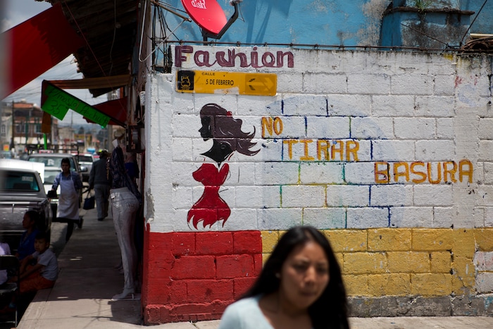 In this Aug. 18, 2017 photo, a woman walks past the wall of a clothing store painted with the figure of a woman as advertising, next to phrase "No dumping garbage," in Villa Cuauhtemoc, Mexico state. "This problem is difficult to eradicate because it is rooted in ideas that assume that we as women are worth less than men, that we as women can be treated like trash," said Dilcya Garcia Espinoza de los Monteros, deputy state prosecutor for gender violence crimes, regarding femicides. (AP Photo/Rebecca Blackwell)