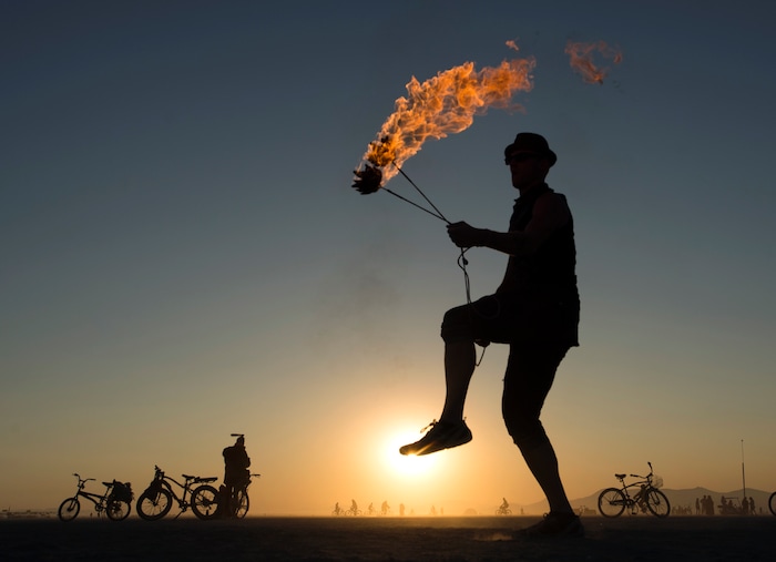 (Rick Egan  |  The Salt Lake Tribune)  Josh McGlamery of Salt Lake City, dances with fire at sunrise, during the Burning Man Festival, Saturday, September 2, 2017.
