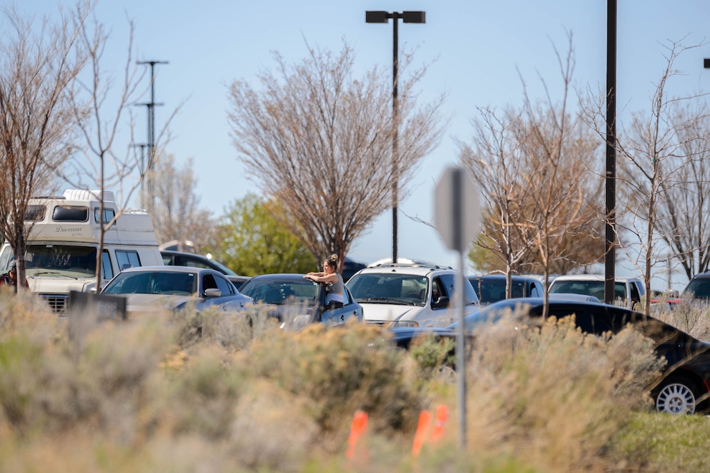 (Trent Nelson | The Salt Lake Tribune) A woman suns herself while waiting in the long line at the South Valley DMV in Draper on Friday, April 10, 2020.