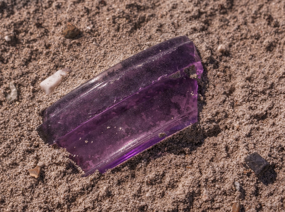 (Leah Hogsten | The Salt Lake Tribune) Broken pieces of purple glass soda bottles from the 1890s can still be found sticking out of the sand near the former location of Saltair, July 21, 2022. Christopher Merritt, a state historic preservation officer, said the Salt Lake City bottling company used a mineral that would turn purple when exposed to sunlight during the glass making process. 