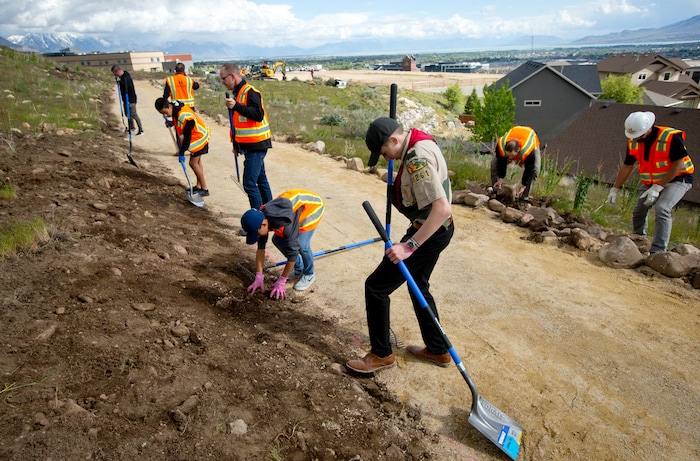 Ethan Blood, 15, of Lehi, packs down soil as he and volunteers help to complete his Eagle Scout Service Project that aims to create a walkable path connecting nearby neighborhoods to Ignite Entrepreneurship Academy and a future park Wednesday, May 8, 2019, just northwest of the charter school in Lehi, Utah. (Isaac Hale/The Daily Herald via AP)