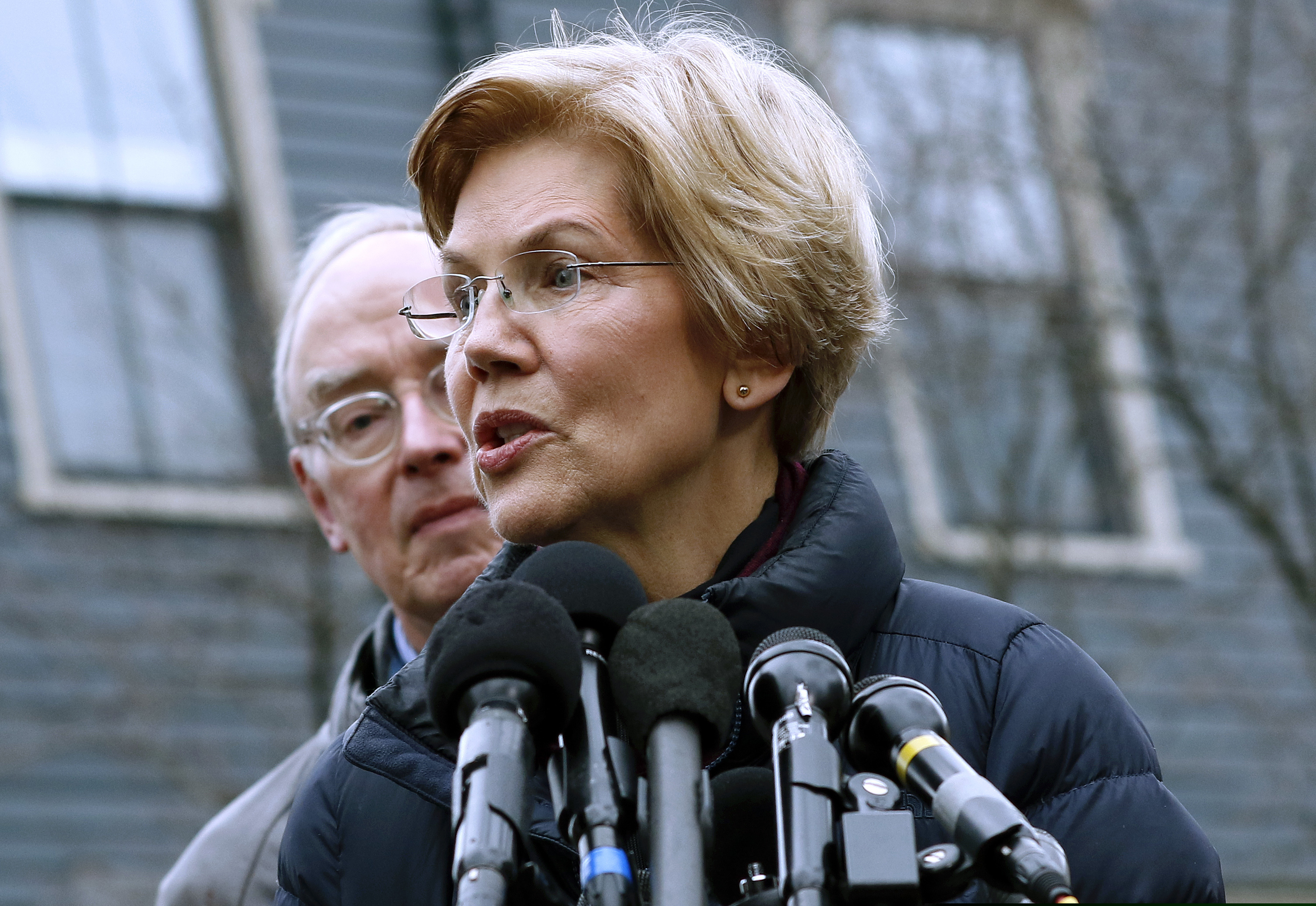 Sen. Elizabeth Warren, D-Mass., speaks beside her husband Bruce Mann, left, outside their home, Monday, Dec. 31, 2018, in Cambridge, Mass., where she confirmed that she is launching an exploratory committee to run for president. Warren on Monday took the first major step toward launching a widely anticipated campaign for the presidency, hoping her reputation as a populist fighter can help her navigate a Democratic field that could include nearly two dozen candidates. (AP Photo/Bill Sikes)