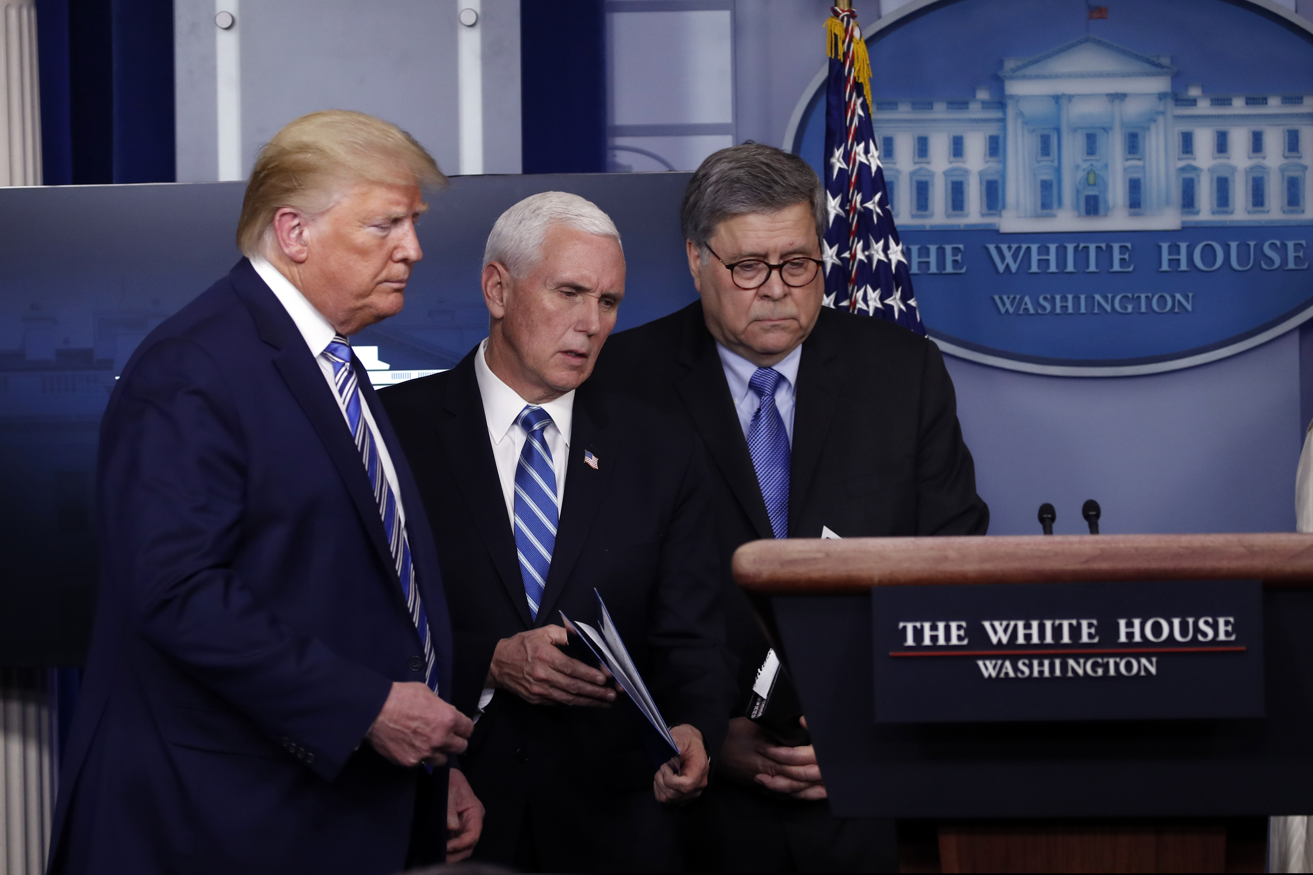 Vice President Mike Pence walks to the podium past President Donald Trump and Attorney General William Barr during a coronavirus briefing in the James Brady Briefing Room, Monday, March 23, 2020, in Washington. (AP Photo/Alex Brandon)