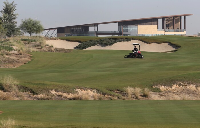 In this Tuesday, Dec. 20, 2016 photo, an employee mows the grass in front of the clubhouse at the Trump International Golf Club, in Dubai, United Arab Emirates. The 18-hole golf course in Dubai bearing Donald Trump’s name exemplifies the questions surrounding his international business interests. The course will open in February 2017 in the United Arab Emirates, but concerns about security, financial agreements and other matters have yet to be answered by the incoming 45th American president. (AP Photo/Kamran Jebreili)