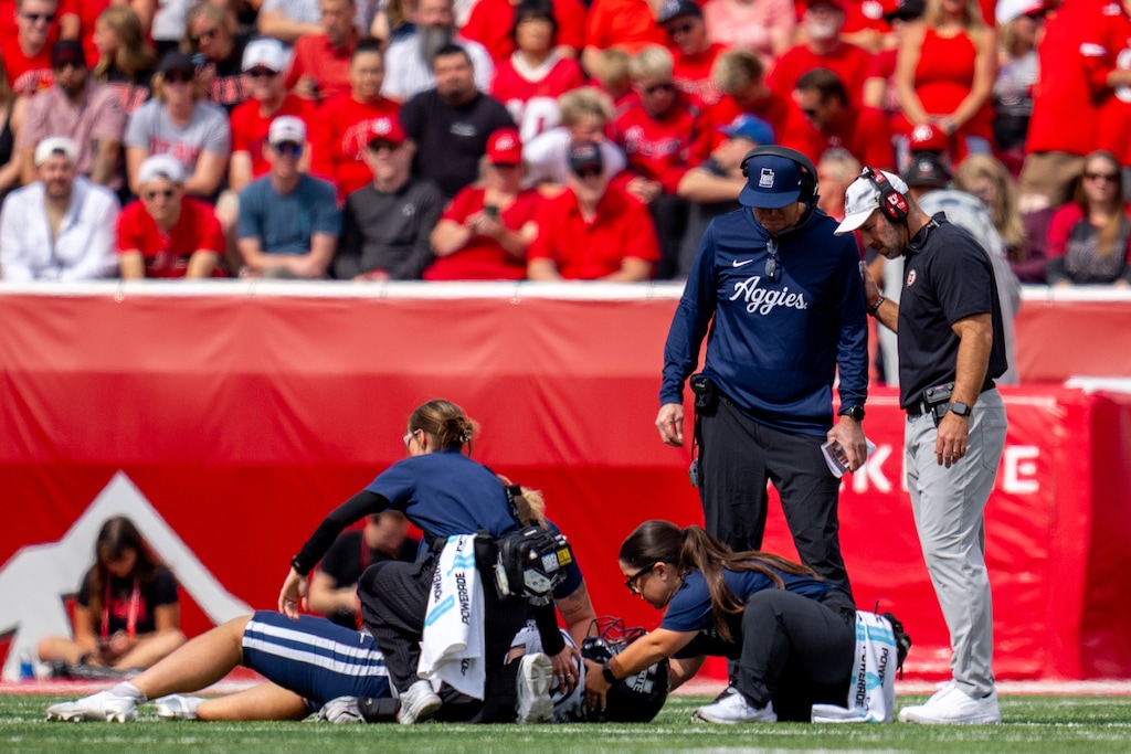 (Trent Nelson  |  The Salt Lake Tribune) Utah State Aggies head coach Bronco Mendenhall and Utah Utes head coach Morgan Scalley look down at an injured Utah State Aggies linebacker, Harrison Taggart (0), as Utah hosts Utah State, NCAA football in Salt Lake City on Saturday, Sept. 19, 2026.