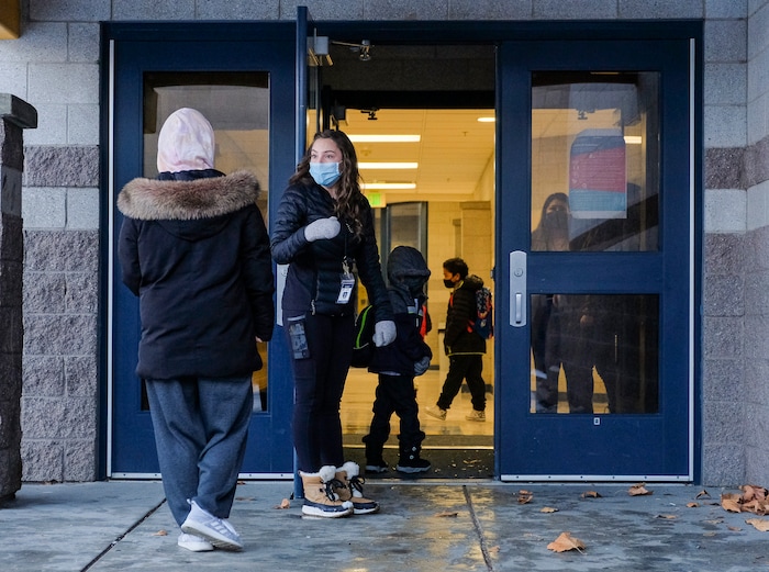 (Leah Hogsten | The Salt Lake Tribune) Teaching assistant Becca Stevens holds the door open for returning Escalante Elementary students in Salt Lake City, January, 25, 2021. Salt Lake City School District reopened all of the district's elementary schools to in-person learning on Monday. It is the first time students in kindergarten through sixth grade are back in the classroom for a full day of school since they first closed for the pandemic in March 2020.