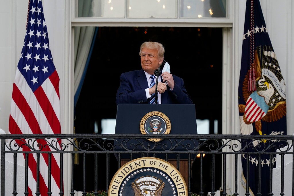 (Alex Brandon | The Associated Press) President Donald Trump removes his face mask to speak from the Blue Room Balcony of the White House to a crowd of supporters, Saturday, Oct. 10, 2020, in Washington.