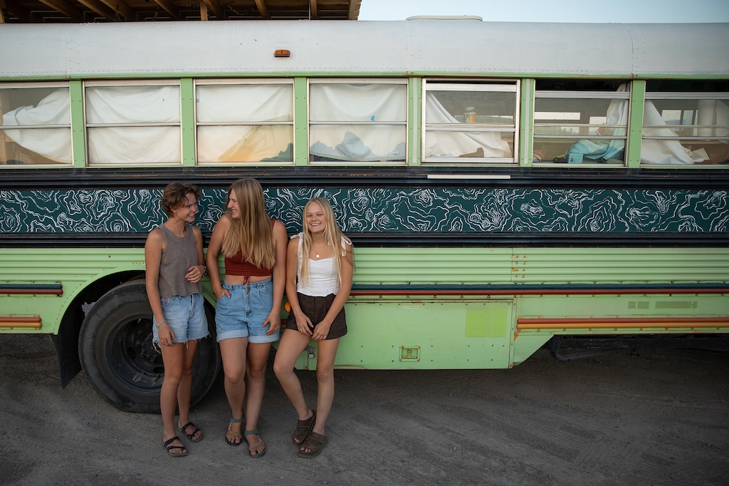 (Keegan Rice | Special to The Tribune) From left, Bekah King, Abi Roberts and Morgan Tabor in their converted school bus outside Jackson, Wyo., Thursday, July 8, 2021. The women, who were all dating the same man, came together after finding out their boyfriend was cheating and realized they shared a dream of traveling the United States in a bus.
