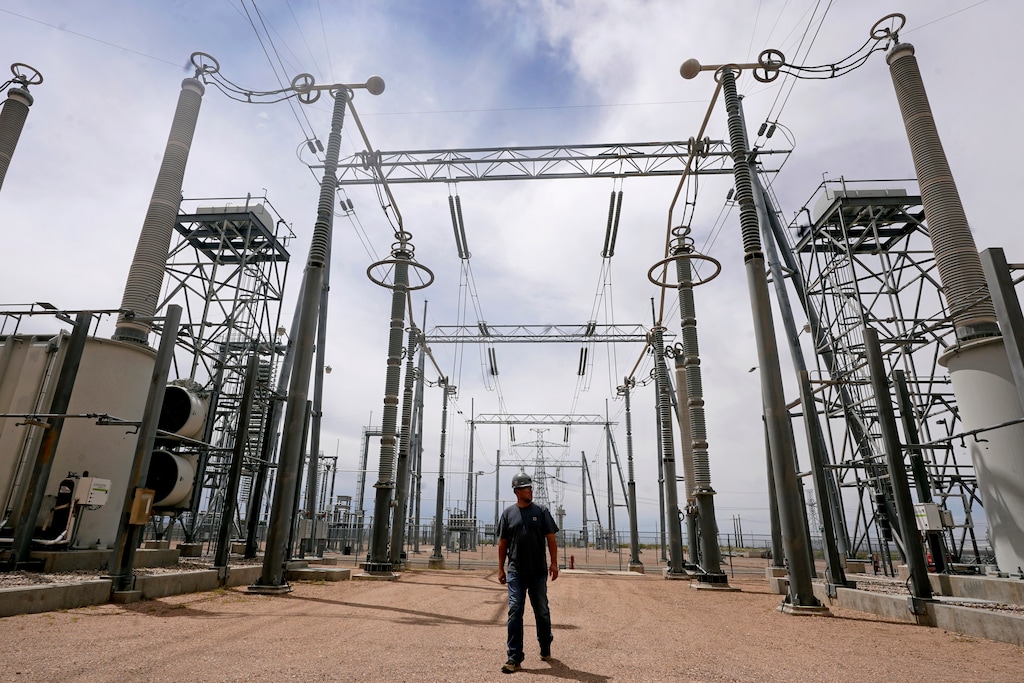 (Rick Bowmer | AP) Cecil Crow walks through an electricity substation at Intermountain Power Plant on Wednesday, June 22, 2022, in Delta, Utah. In three years, the power lines will start being used to transport power generated with hydrogen to consumers in California and elsewhere.
