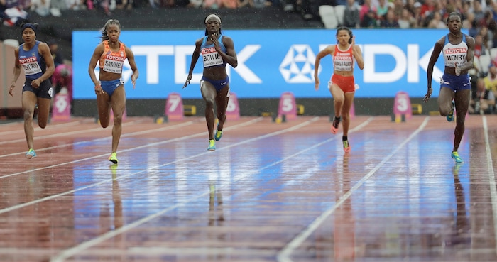 United States' Tori Bowie, center, runs through the rain in a Women's 100m first round heat during the World Athletics Championships in London Saturday, Aug. 5, 2017. (AP Photo/David J. Phillip)