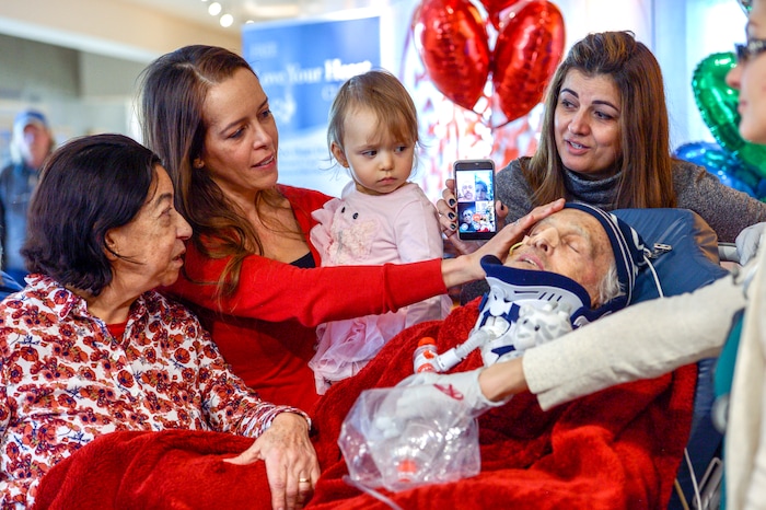 Leah Hogsten  |  The Salt Lake Tribune  l-r Lucia Silva, daughter Flavia Beare, granddaugher Petra Beare, and family friend Cristina Tesolin caress the face of their husband and father, Osvaldo Silva. On Friday, Intermountain Hospital caregivers wheeled paralyzed cancer patient Osvaldo Silva, 85, down to the lobby for a personal piano concert in his honor, Feb. 15, 2019. With tears streaming down his face, Osvaldo, who is from Brazil, was treated to a dozen songs played by his Church of Jesus Christ of Latter-day Saints bishop, Bispo Do Pai Valdir, who kicked off the set with none other than ÒThe Girl from Ipanema.Ó  