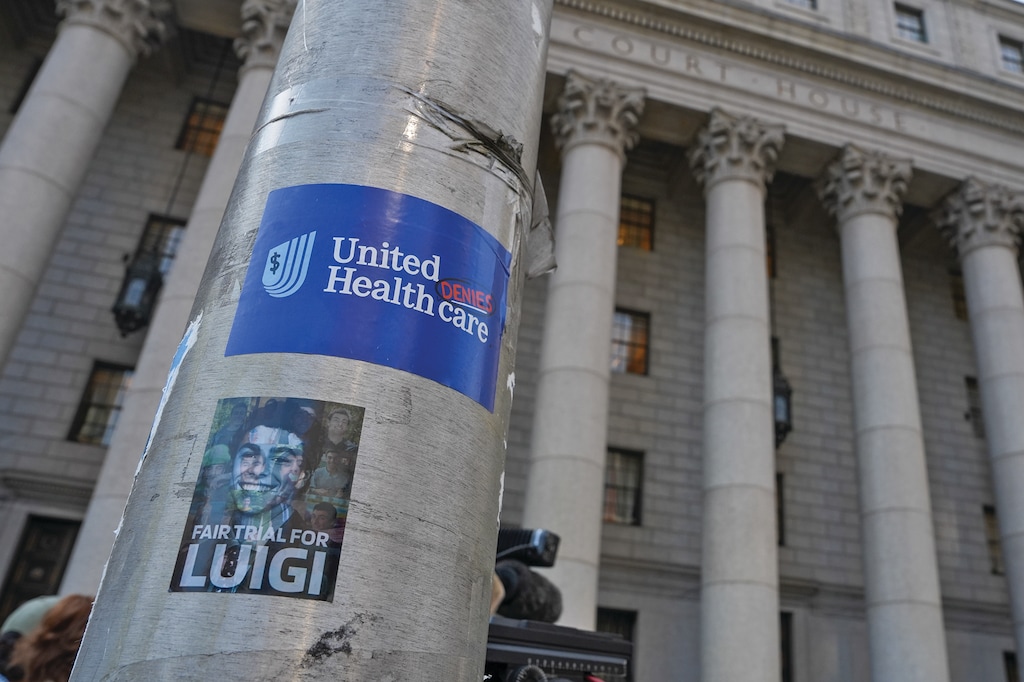 Stickers are displayed on a pole in front of Manhattan federal court on the day of a hearing for Luigi Mangione on Friday, Aug. 14, 2026, in New York. (AP Photo/Ryan Murphy)