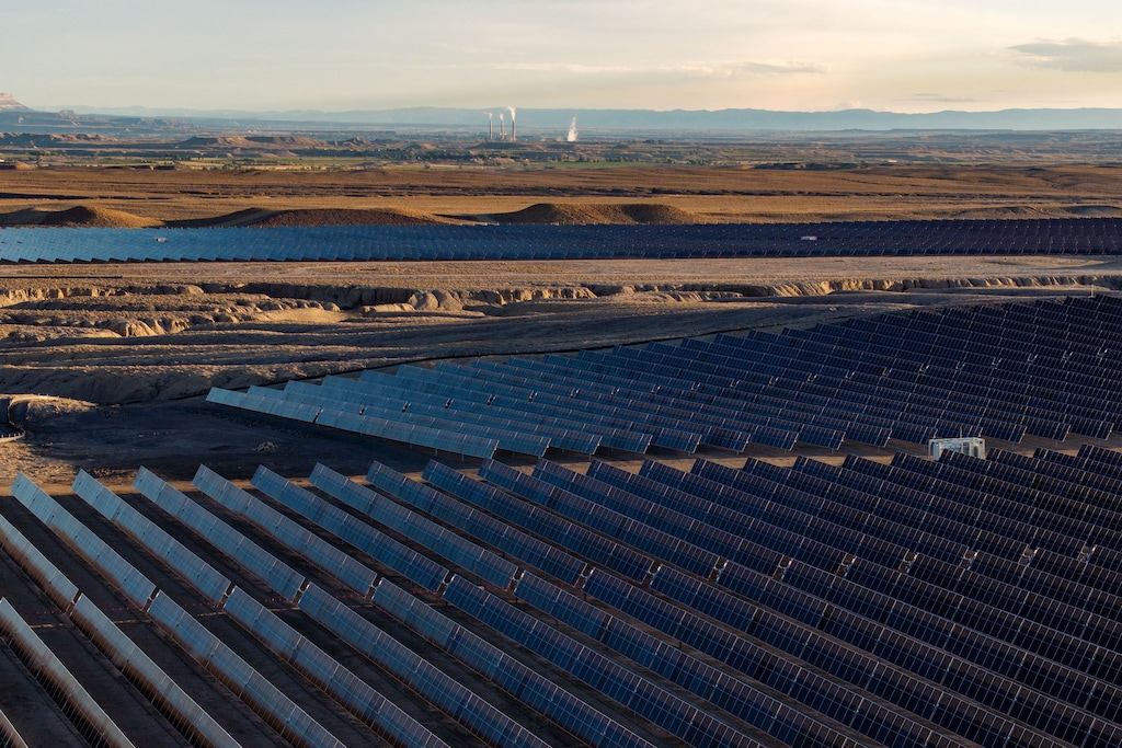 (Photo courtesy of rPlus Energies) Solar panels at the Green River Energy Center stretch across the desert in Emery County, with the Hunter coal-fired power plant visible in the distance.