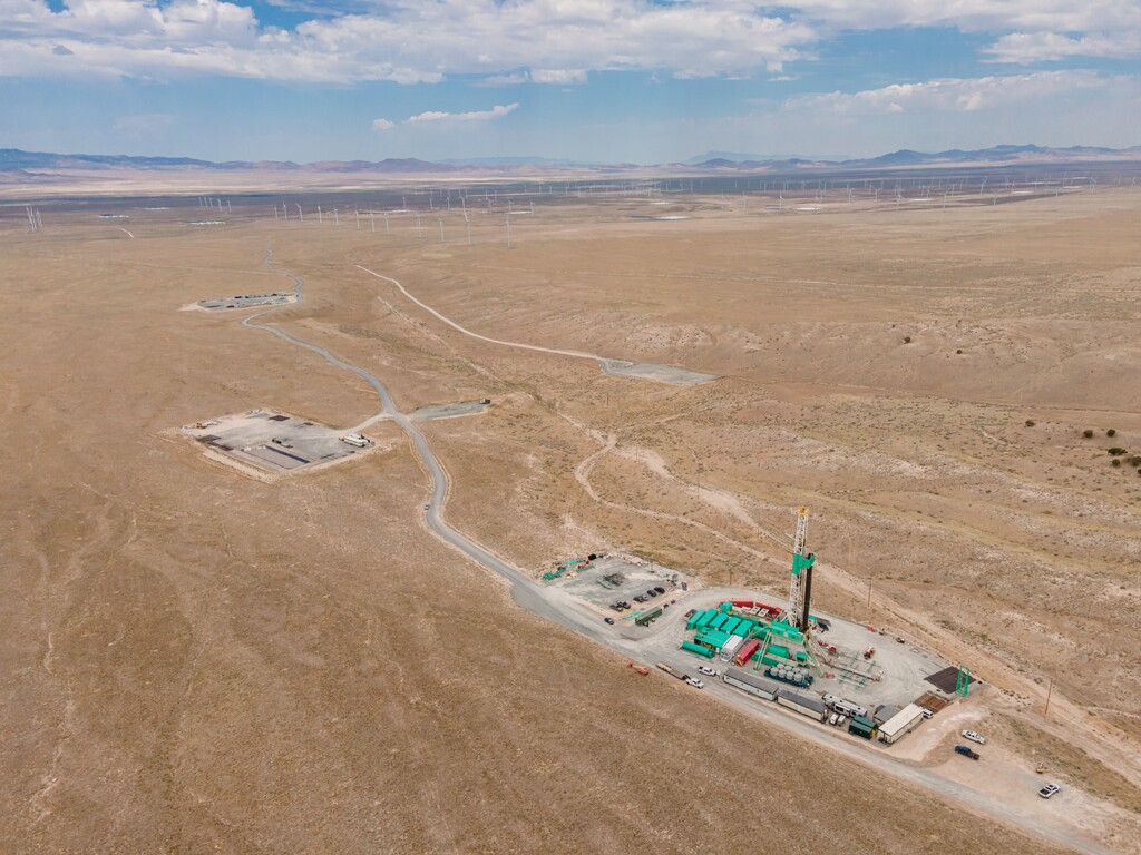 (Eric Larson | FlashPoint SLC) The buildings and drill rig of the Utah FORGE project stand out from the desert floor near Milford, Utah. In the background are some of Beaver County's power-generating windmills.