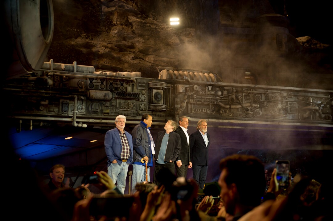 (Jeremy Harmon  |  The Salt Lake Tribune) Mark Hamill peaks back at the Millennium Falcon as he participates in the dedication ceremony for Star Wars: Galaxy's Edge in Anaheim, Ca. on Wednesday, May 29, 2019. On stage with him are George Lucas, Billy Dee Williams, Disney CEO Bob Iger and Harrison Ford.