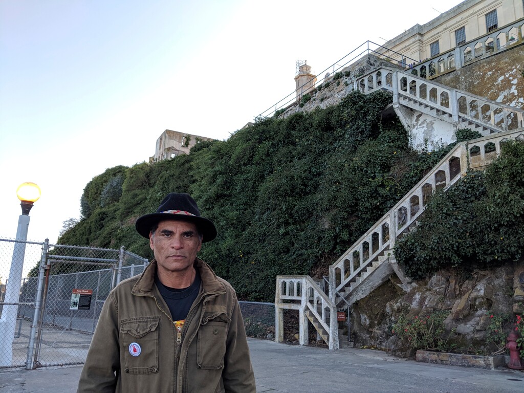 (Patty Talahongva | Indian Country Today via AP) This Thursday, Nov. 21, 2019 photo shows Alan Harrison poses for a photo on Alcatraz Island in San Francisco. Eight-year-old Harrison was sound asleep on Nov. 20, 1969, when he was roused from bed at two in the morning by his mother. "She told me that we were going camping. I loved camping, so we grabbed our sleeping bags, fishing poles and were really happy about it," Harrison said. "We got on a boat that left from Sausalito. When we arrived, my mom took us to the warden's office because it was the only room that was carpeted, and she didn't want us sleeping on the concrete."