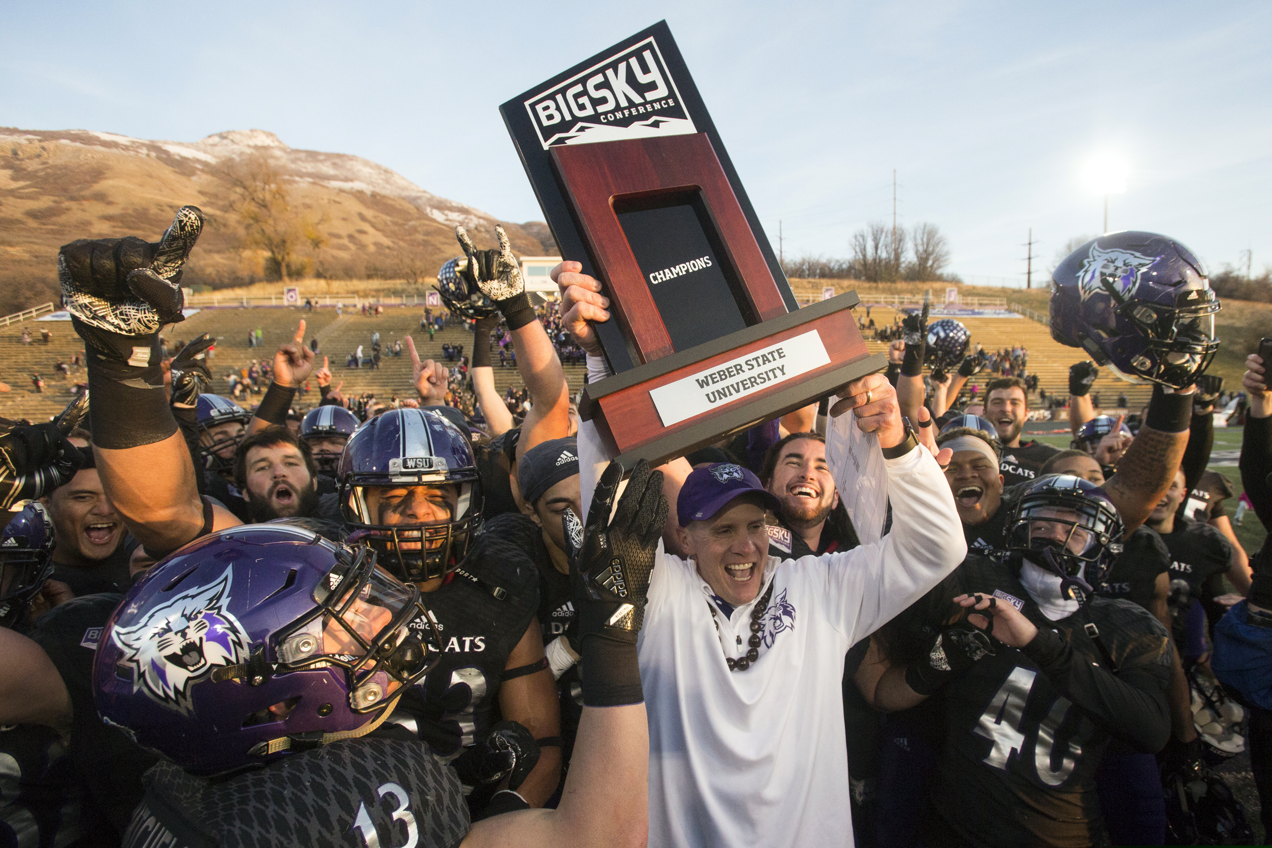 (The Associated Press) In this Nov. 18, 2017, file photo, Weber State coach Jay Hill hoists the trophy after they defeated Idaho State in an NCAA college football game for a share of the Big Sky Conference title in Ogden, Utah.