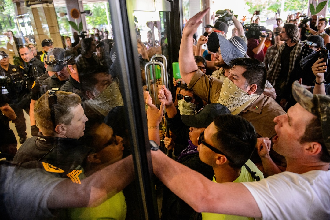 (Trent Nelson  |  The Salt Lake Tribune) Police struggle with Inland Port protesters for control of a door at the Chamber of Commerce Building Salt Lake City on Tuesday, July 9, 2019.