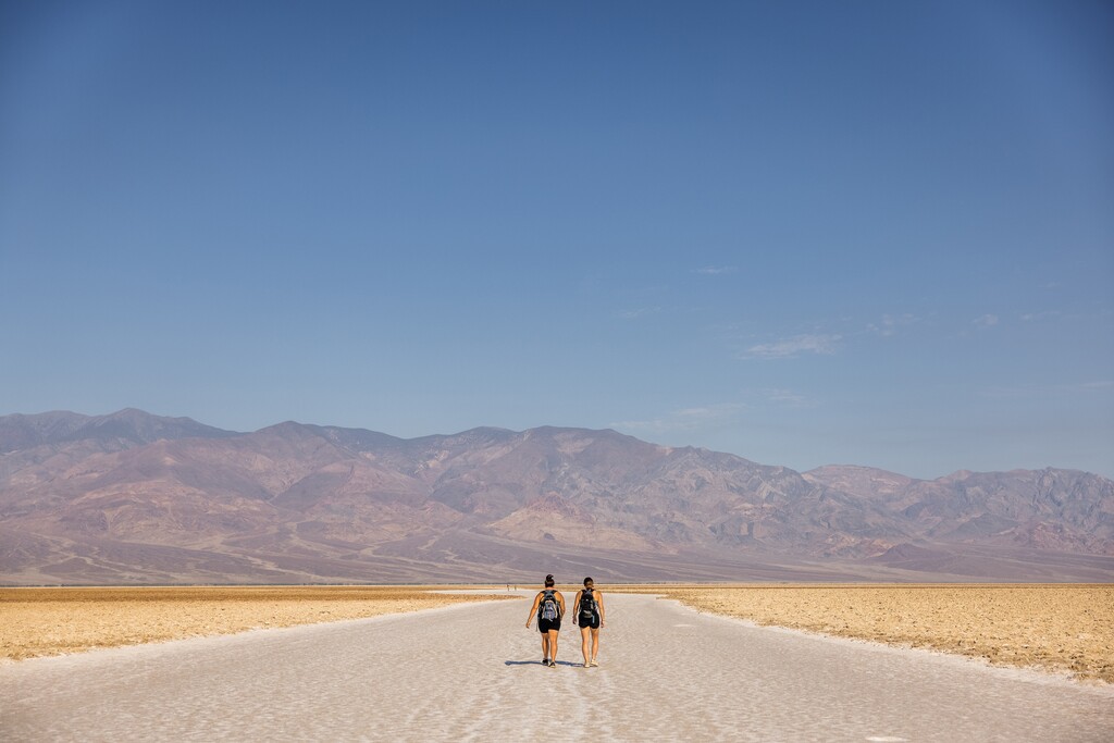 (Roger Kisby | The New York Times) Ashley Dehetre and Katelyn Price, walk on the salt flats of Badwater Basin in Death Valley, Calif., on July 10, 2021, after a 33-hour road trip from Detroit. Much of the West again faces record-breaking temperatures over the coming days, with over 31 million people in areas under either an excessive heat warning or a heat advisory. It is the third heat wave to sweep the region this summer.