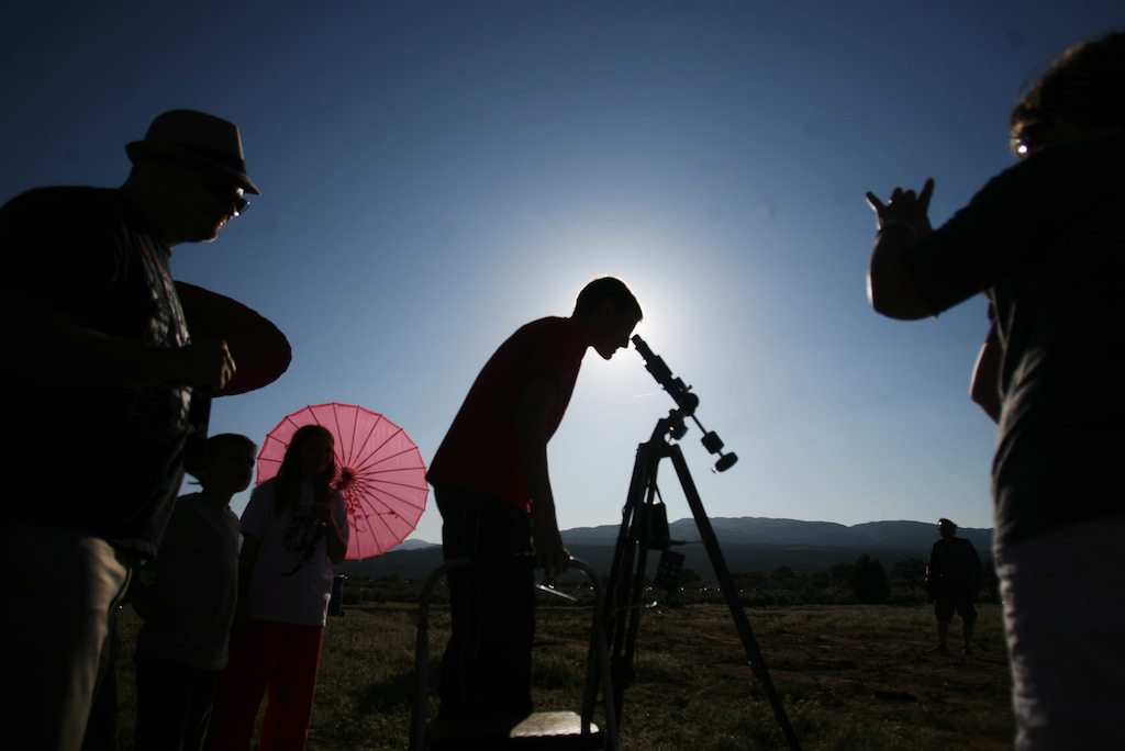 (Kim Raff | Salt Lake Tribune file photo) Jake Rehkop looks through a telescope as people view an annular solar eclipse in Kanarraville on May 20, 2012. An annular eclipse is scheduled to cross over southern Utah on Oct. 14, 2023, and tourists are expected to flock to locations like Torrey and Richfield, which fall into the eclipse's path of totality.