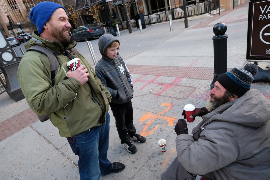 (Francisco Kjolseth  |  The Salt Lake Tribune) Ten-year-old Chase Hansen and his father John bring Chris Coons a coffee as he panhandles in downtown Salt Lake City on Monday, Dec. 16, 2019. Chase who was six when they started Project Empathy, spend time with people experiencing homelessness in an effort to connect with people on a personal level.
