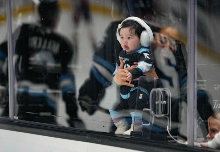 (Francisco Kjolseth | The Salt Lake Tribune) Marissa Kerfoot holds her daughter Carrera as they watch the Utah Hockey Club warm up before their game against the Washington Capitals during an NHL hockey game at the Delta Center in Salt Lake City on Monday, Nov. 18, 2024.